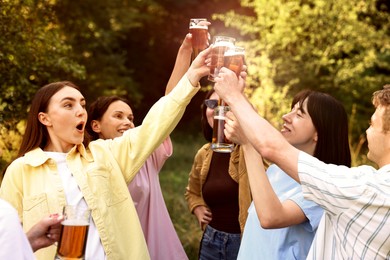 Photo of Group of happy friends clinking glasses of beer outdoors