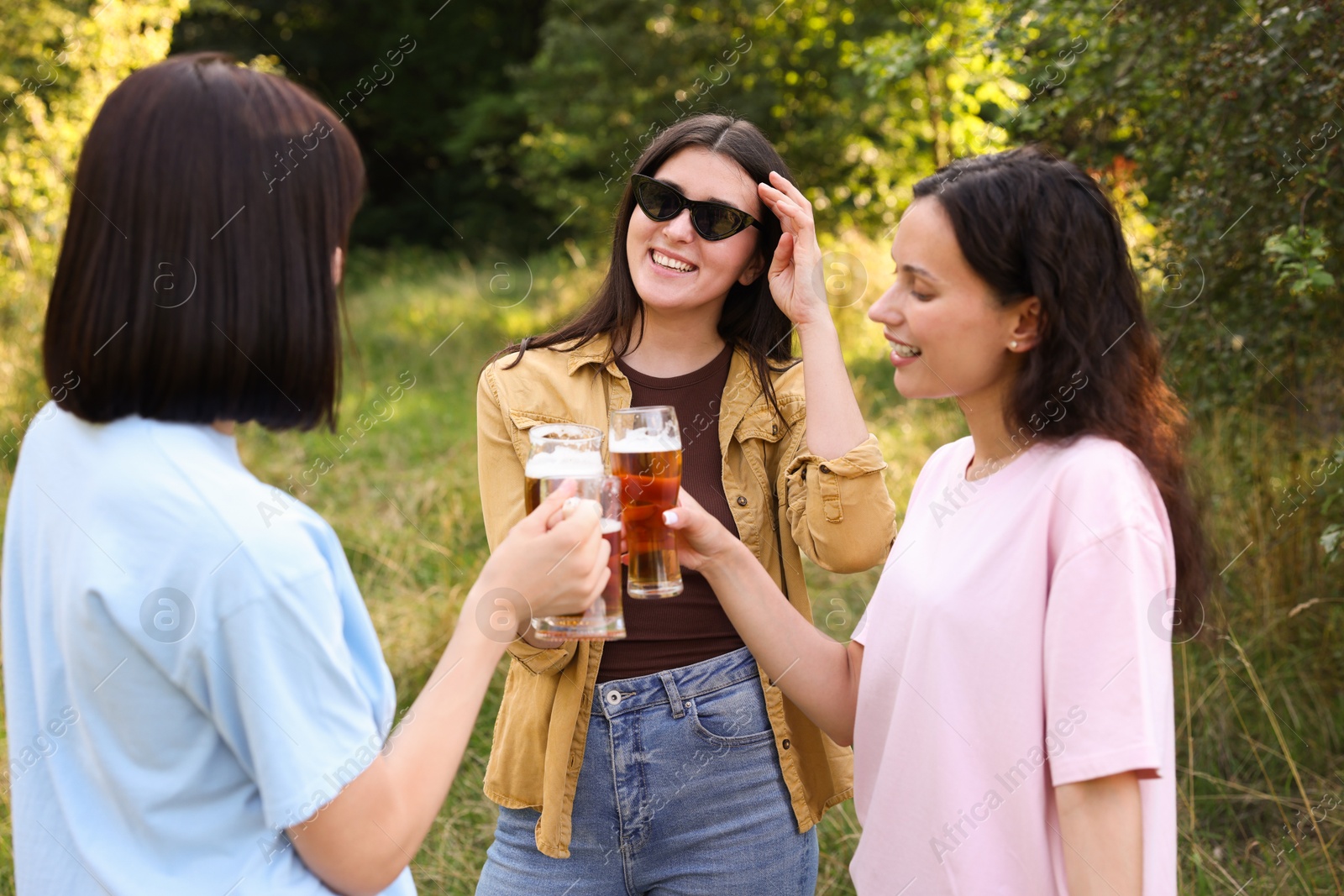Group of happy friends clinking glasses of beer outdoors Photo of Group of happy friends clinking glasses of beer outdoors