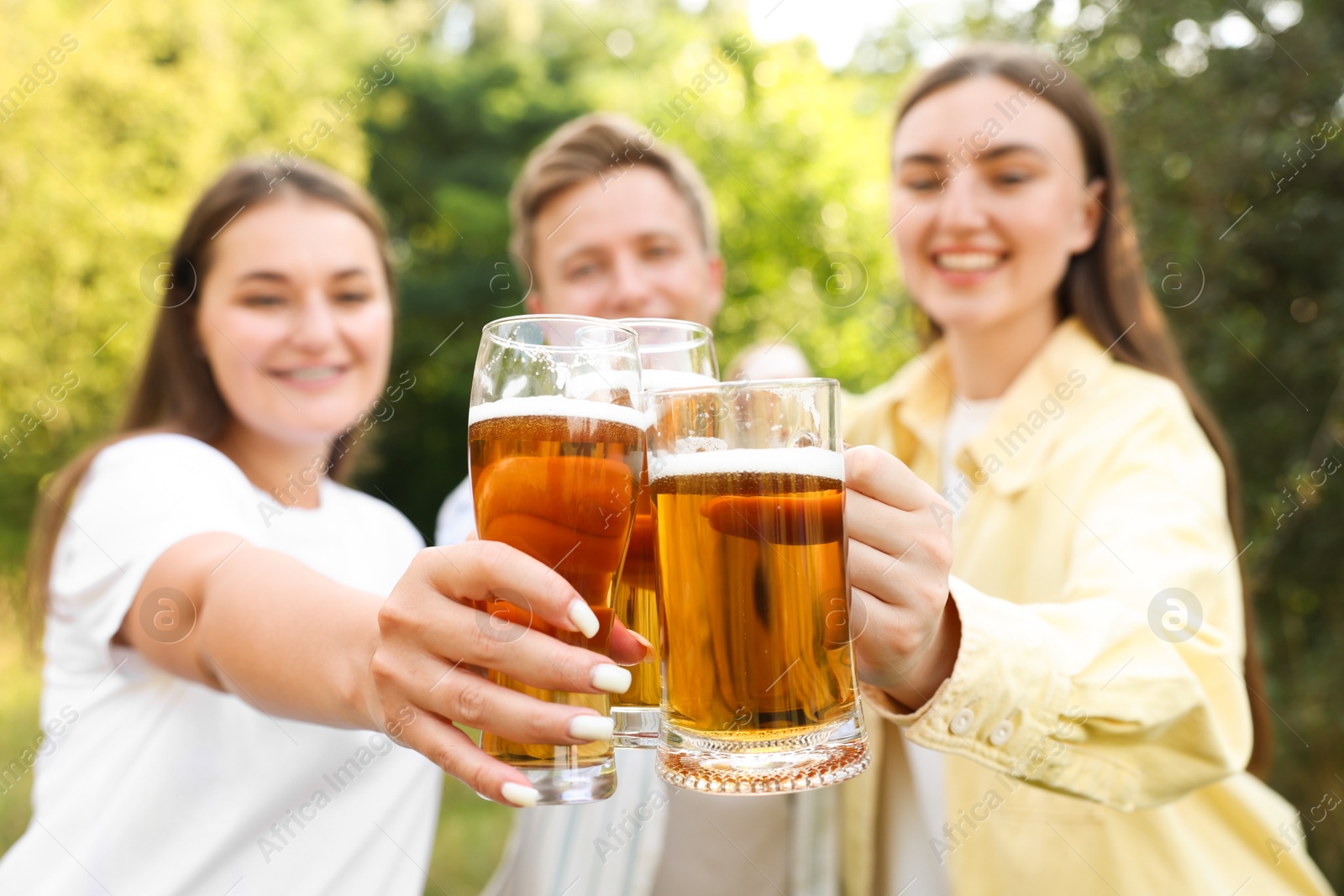 Group of happy friends clinking glasses of beer outdoors, selective focus Photo of Group of happy friends clinking glasses of beer outdoors, selective focus