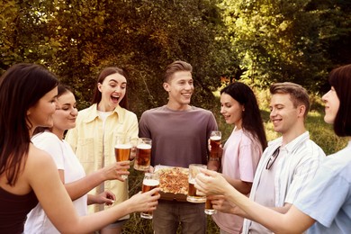 Photo of Group of happy friends with pizza having fun and drinking beer outdoors