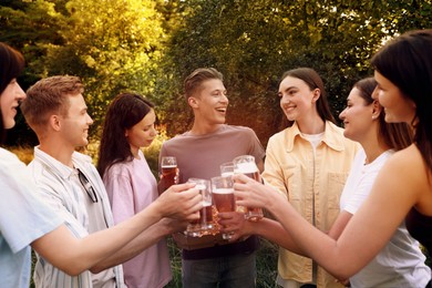 Photo of Group of happy friends with pizza clinking glasses of beer outdoors