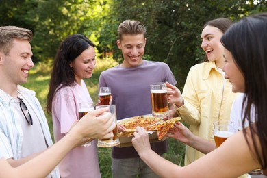 Photo of Group of happy friends with pizza having fun and drinking beer outdoors