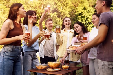 Photo of Group of happy friends having fun and drinking beer outdoors