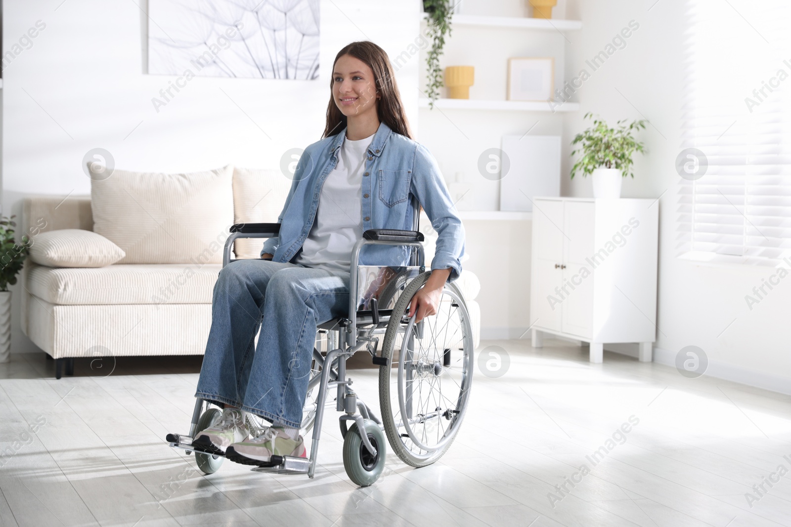 Photo of Smiling teenage girl in wheelchair at home