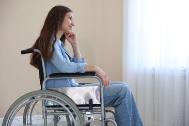Photo of Smiling teenage girl in wheelchair near window indoors