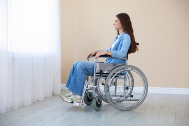 Photo of Smiling teenage girl in wheelchair near window indoors