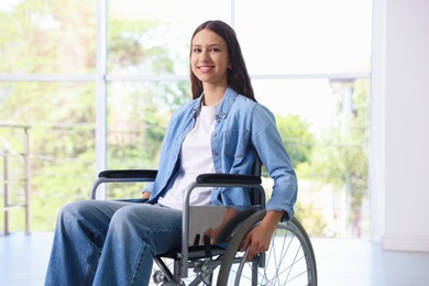 Photo of Smiling teenage girl in wheelchair near window indoors