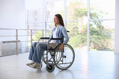 Photo of Smiling teenage girl in wheelchair near window indoors
