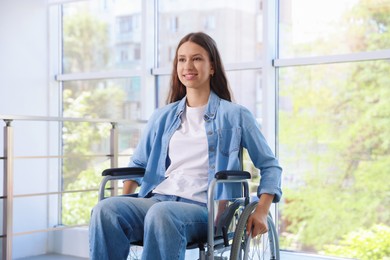 Photo of Smiling teenage girl in wheelchair near window indoors