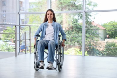 Photo of Smiling teenage girl in wheelchair near window indoors