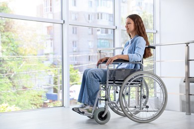 Photo of Smiling teenage girl in wheelchair near window indoors