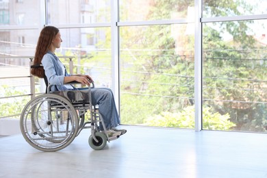 Photo of Teenage girl in wheelchair near window indoors. Space for text
