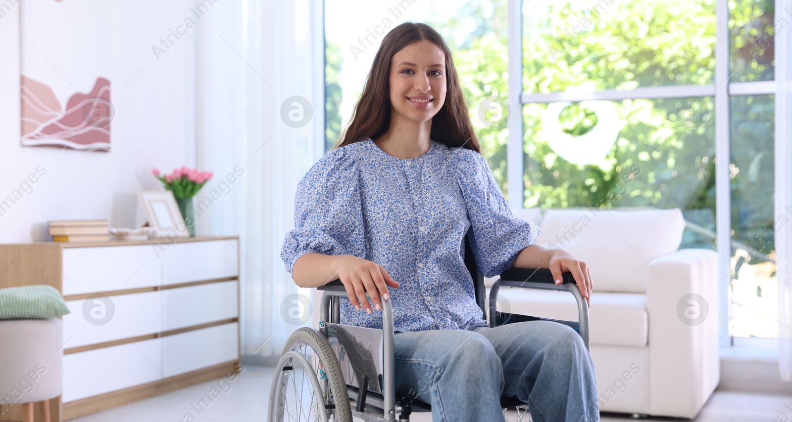 Photo of Smiling teenage girl in wheelchair at home