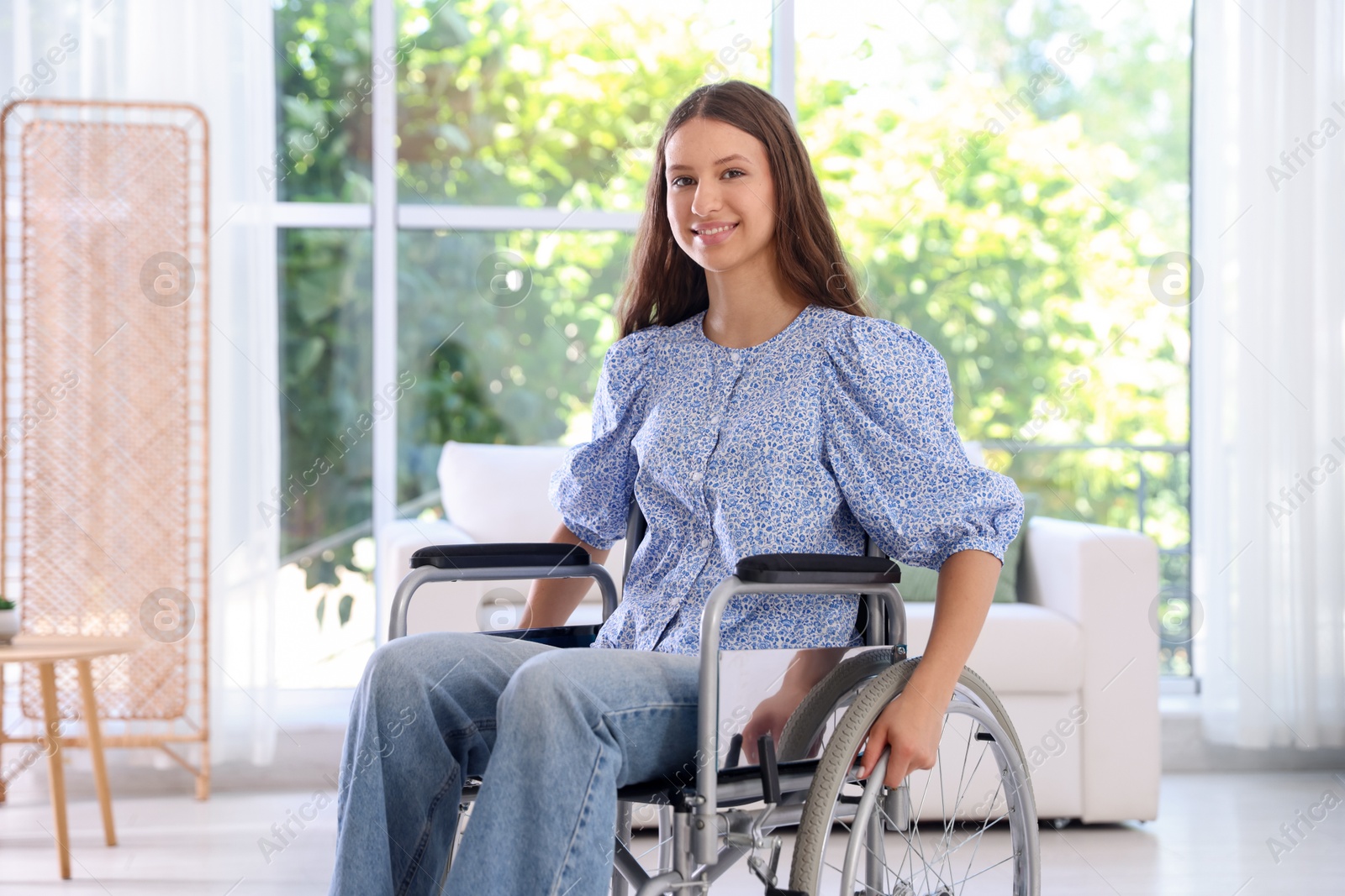 Photo of Smiling teenage girl in wheelchair at home