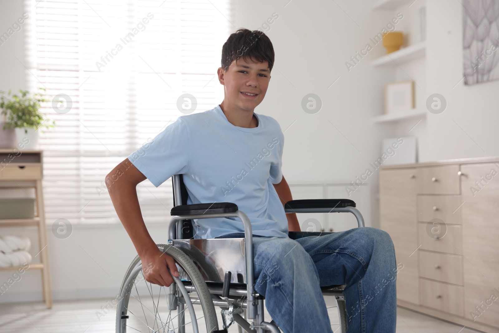 Photo of Happy teenage boy in modern wheelchair indoors