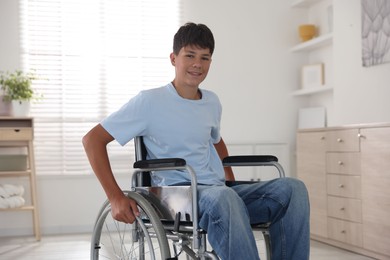 Photo of Happy teenage boy in modern wheelchair indoors