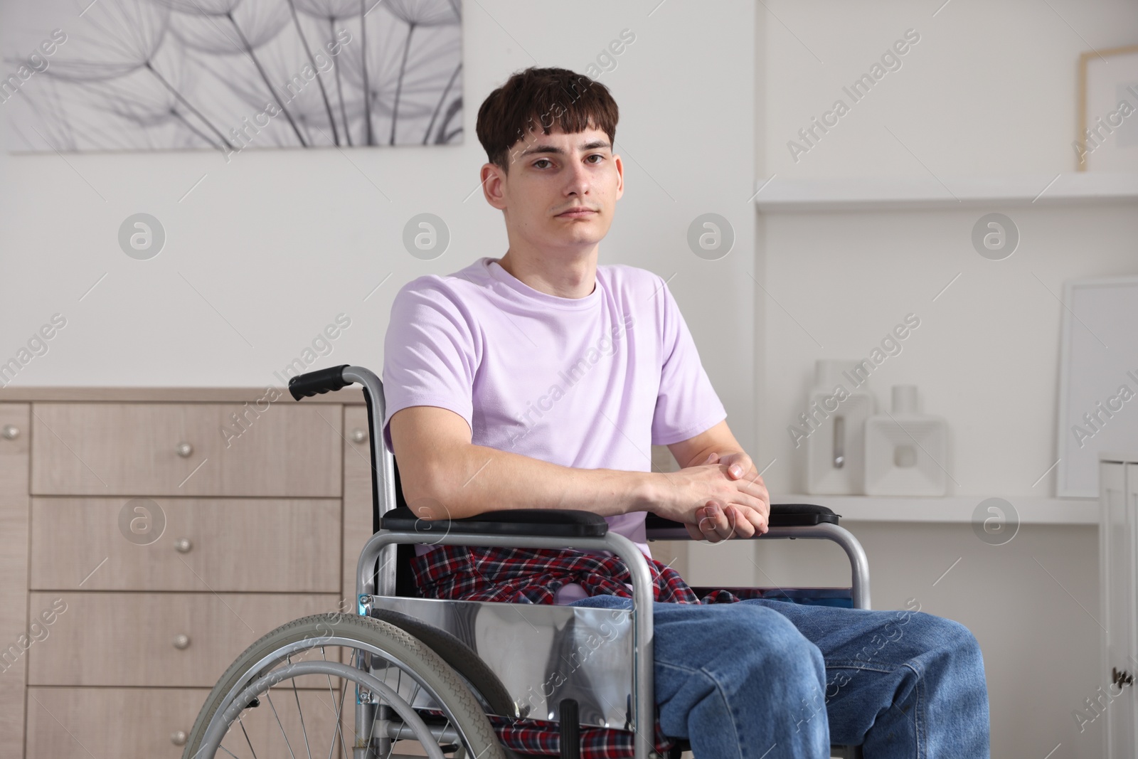Photo of Young man in modern wheelchair at home