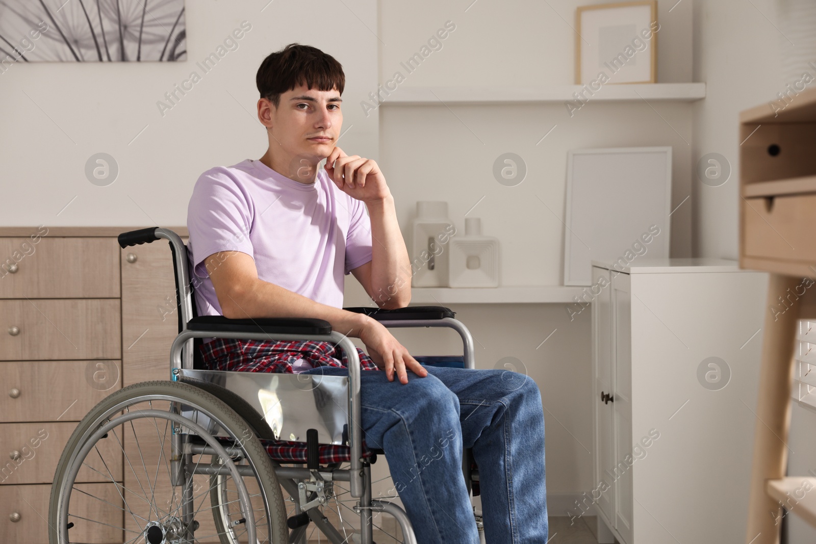 Photo of Young man in modern wheelchair at home