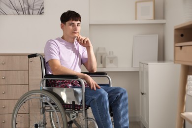 Photo of Young man in modern wheelchair at home