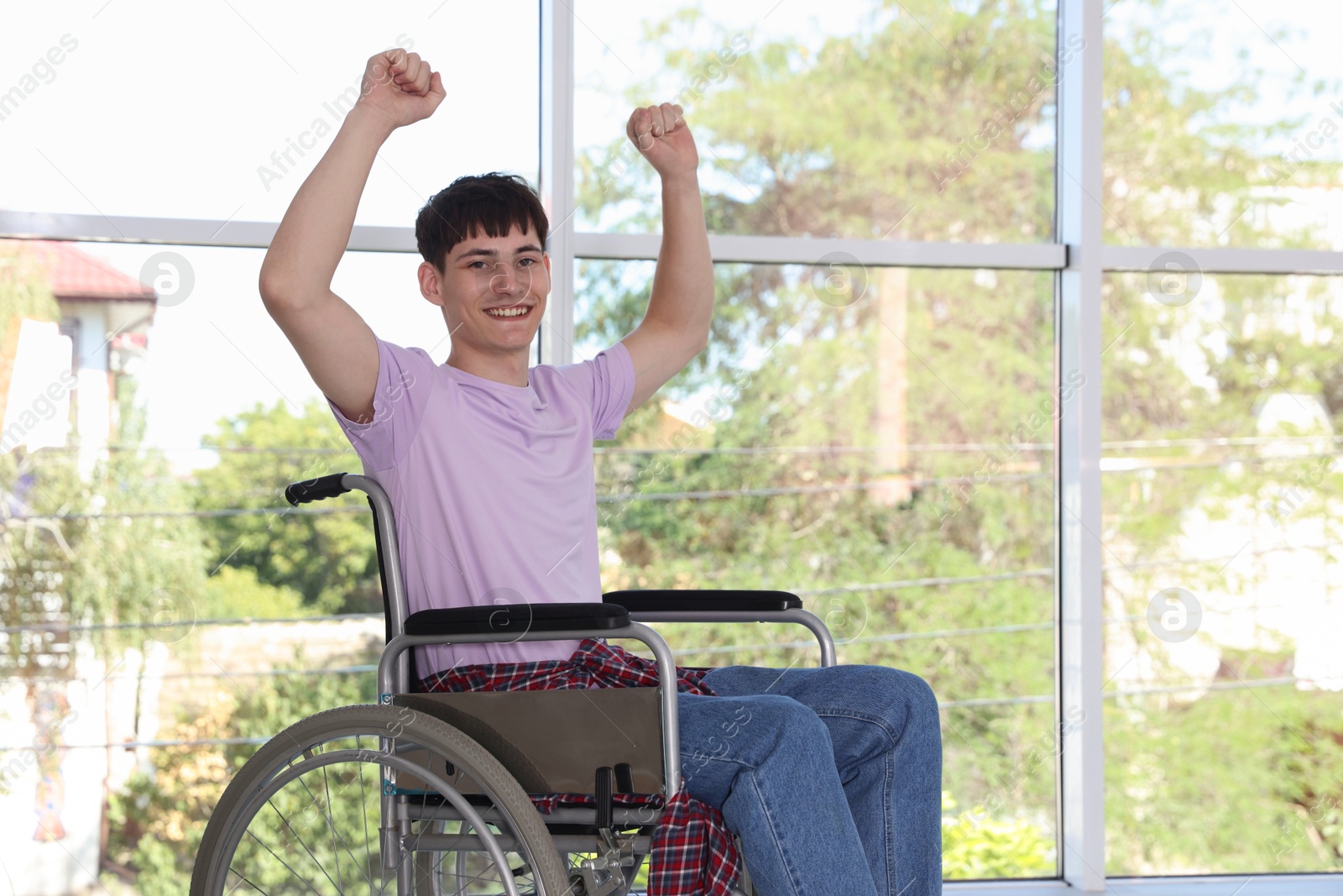 Photo of Happy young man in modern wheelchair indoors, space for text