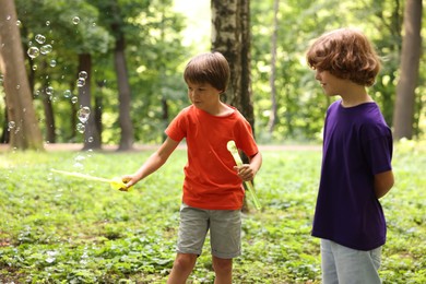Photo of Cute little kids having fun with soap bubbles in park