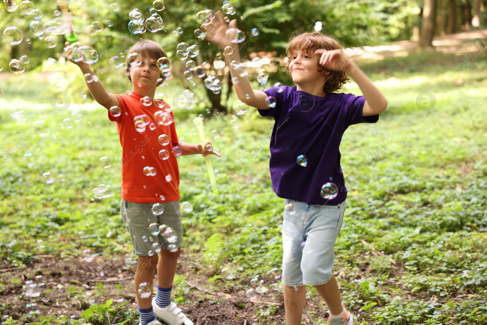 Photo of Cute little kids having fun with soap bubbles in park