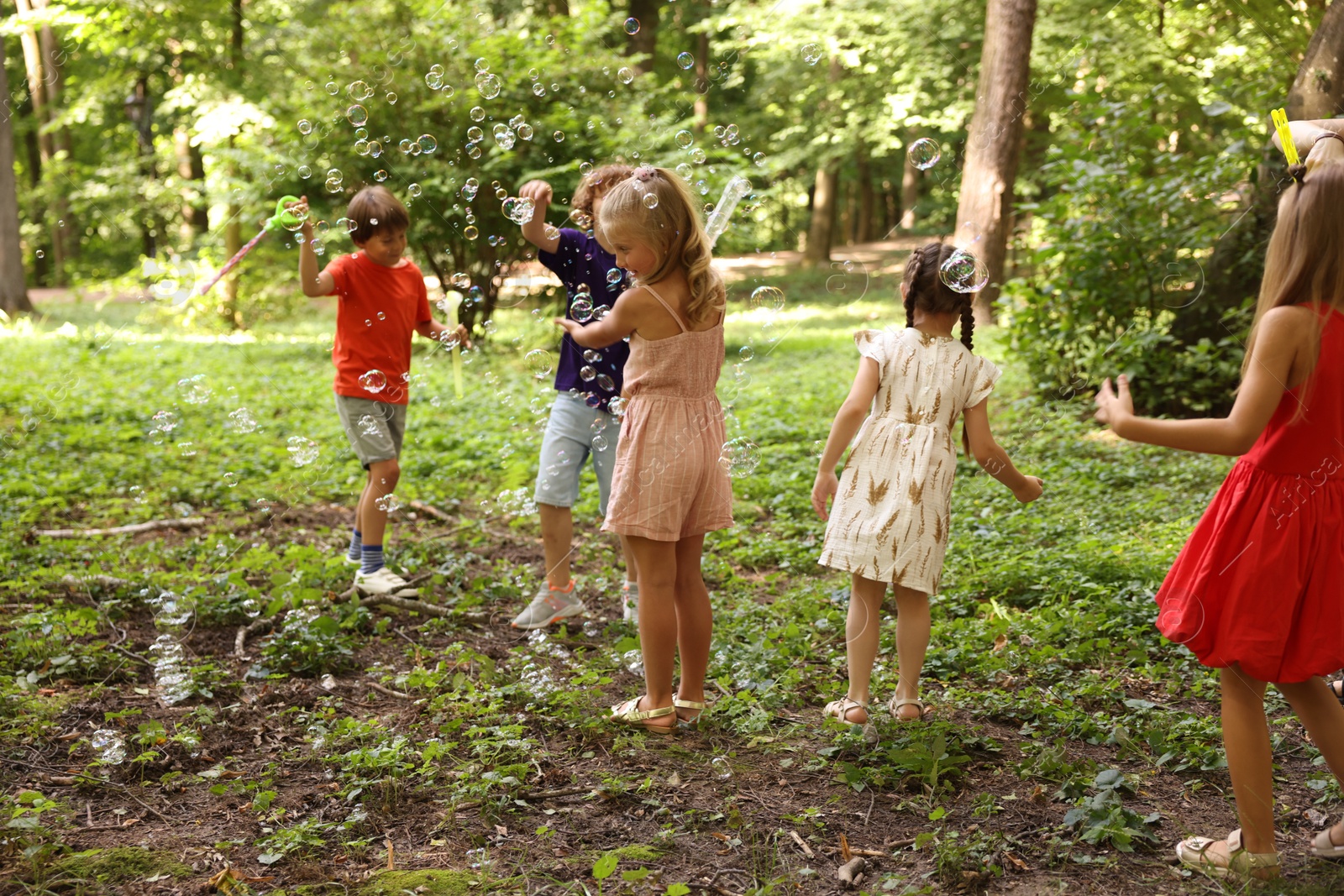 Photo of Cute little kids having fun with soap bubbles in park
