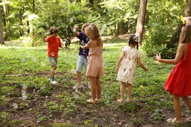 Photo of Cute little kids having fun with soap bubbles in park