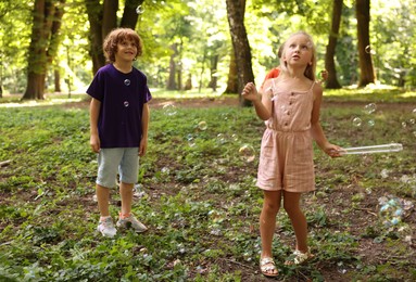 Photo of Cute little kids having fun with soap bubbles in park