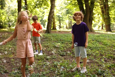 Photo of Cute little kids having fun with soap bubbles in park