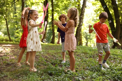 Photo of Cute little kids having fun with soap bubbles in park