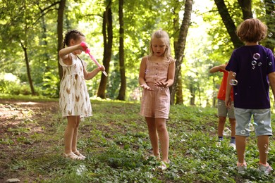 Photo of Cute little kids having fun with soap bubbles in park