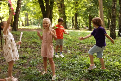 Photo of Cute little kids having fun with soap bubbles in park
