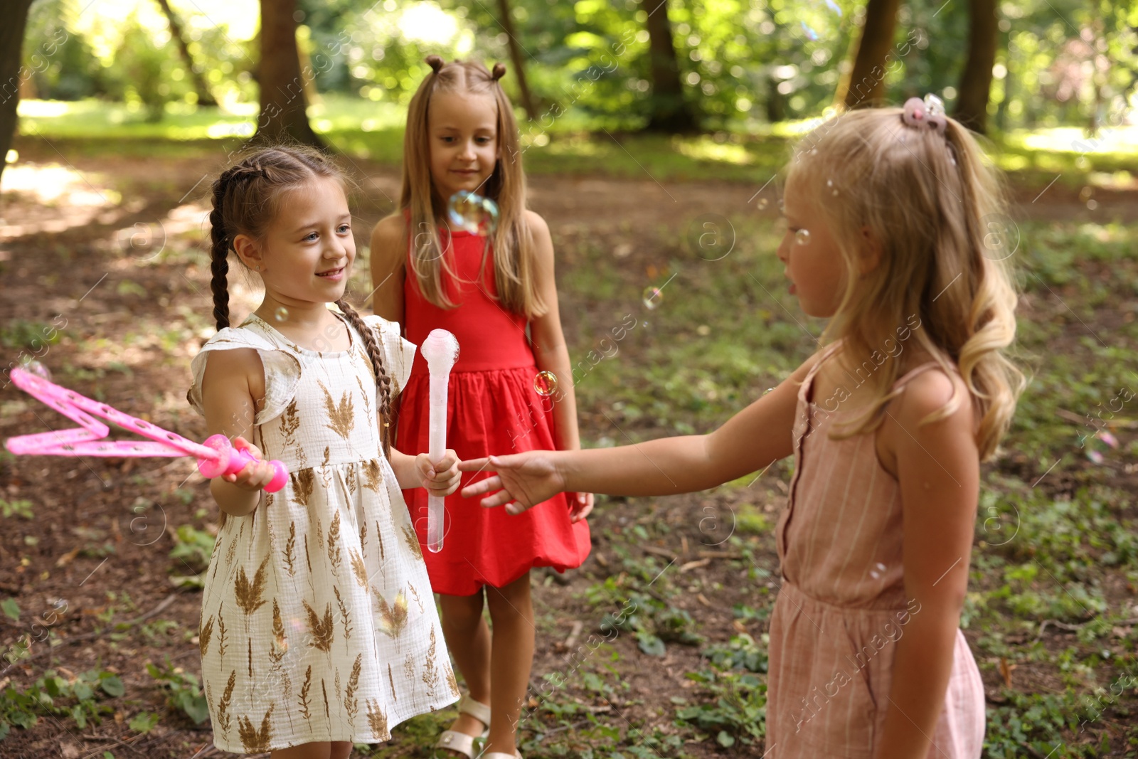 Photo of Cute little kids having fun with soap bubbles in park