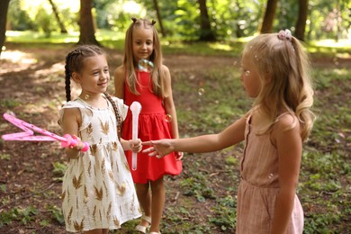 Photo of Cute little kids having fun with soap bubbles in park