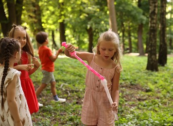 Photo of Cute little kids having fun with soap bubbles in park, selective focus