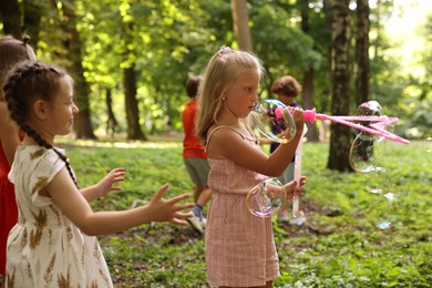Photo of Cute little kids having fun with soap bubbles in park, selective focus