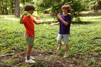 Photo of Cute little kids having fun with soap bubbles in park