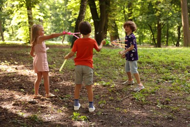 Photo of Cute little kids having fun with soap bubbles in park