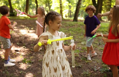 Photo of Cute little kids having fun with soap bubbles in park, selective focus