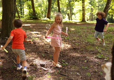 Photo of Cute little kids having fun with soap bubbles in park