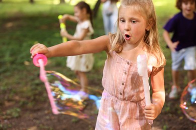 Photo of Cute little kids having fun with soap bubbles in park, selective focus
