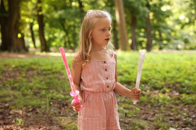 Photo of Cute little girl with bubble wands in park