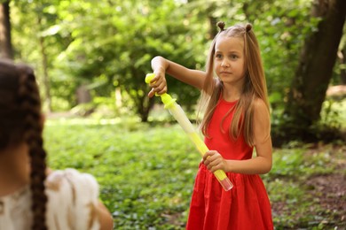 Photo of Cute little girl with bubble wand in park