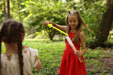 Photo of Cute little girls with bubble wands in park, selective focus