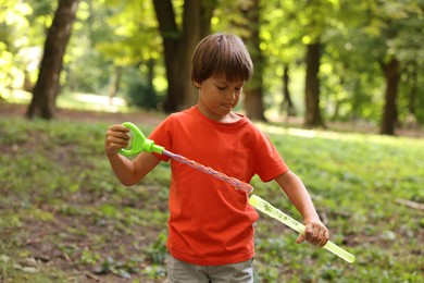 Photo of Cute little boy with bubble wand in park