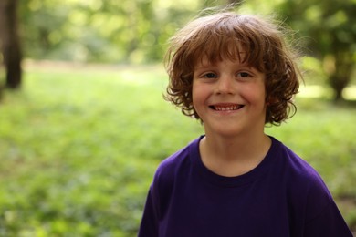 Photo of Portrait of cute little boy in park, space for text
