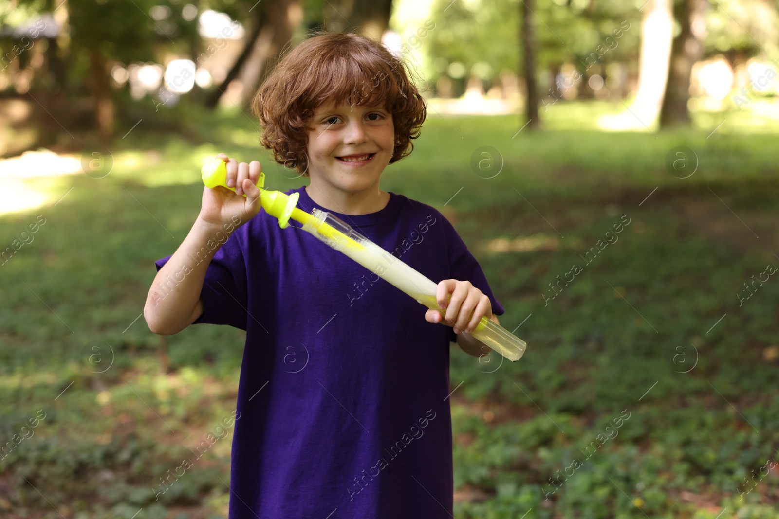 Photo of Cute little boy with bubble wand in park