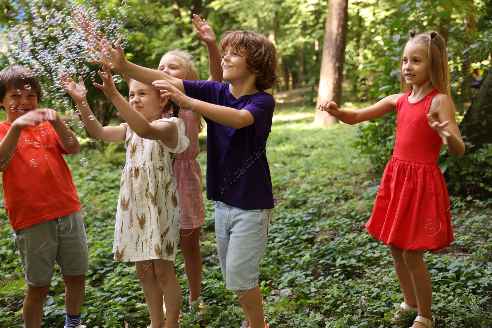 Photo of Cute little kids having fun with soap bubbles in park