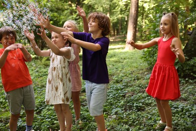Photo of Cute little kids having fun with soap bubbles in park